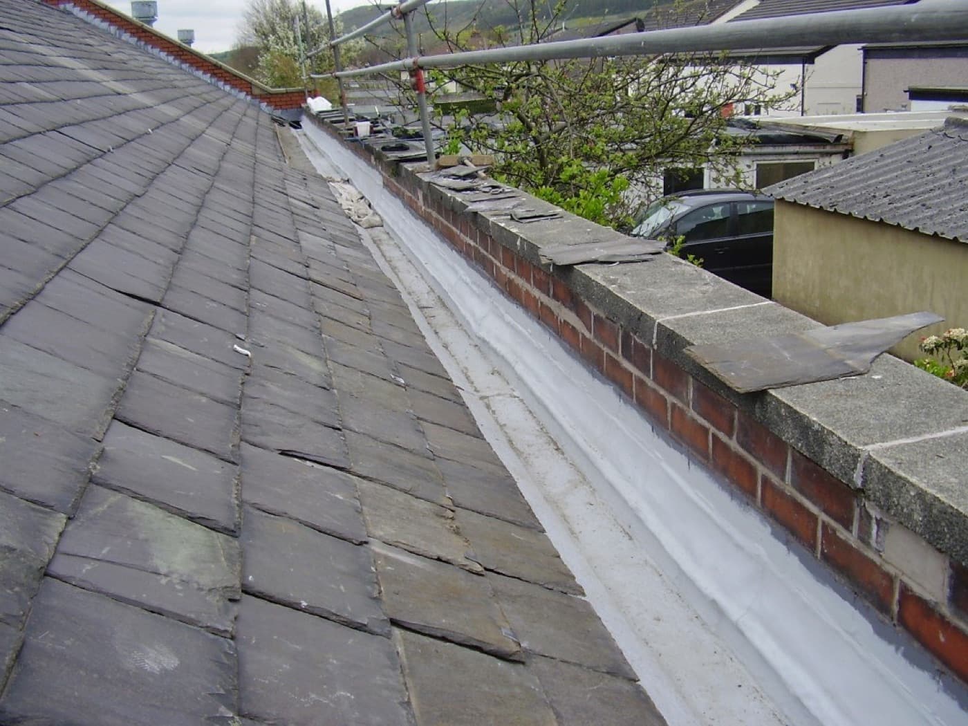 Roof flashing and gutter detail sealed before the membrane coat.